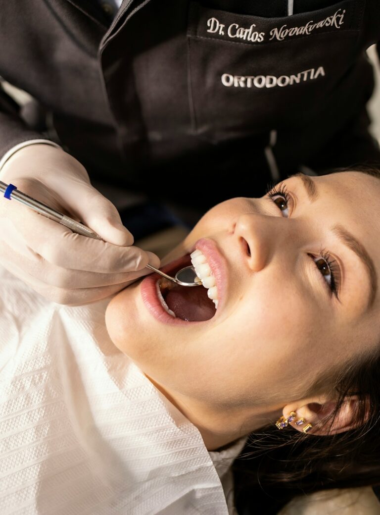 A patient sitting comfortably in a dental chair while a dentist explains a dental X-ray on a monitor.